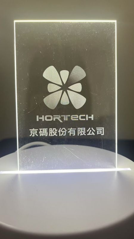 Unsichtbare lasergravierte Muster auf lichtsteuerndem Acryl - Hortech nutzt seine Lasergravurtechnologie, um sein Logo auf einer dünnen, transparenten Platte zu erstellen.